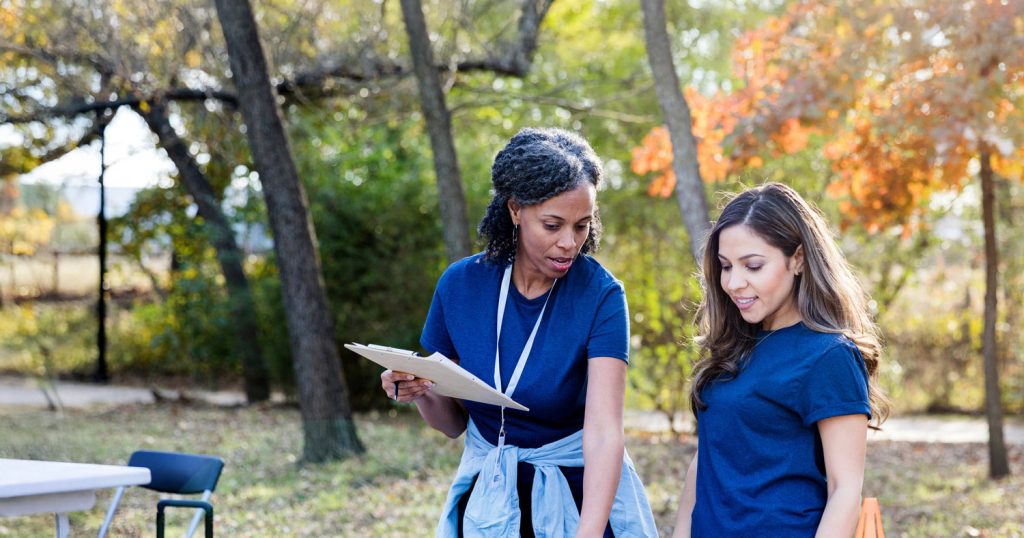 Two volunteers reviewing a clipboard at a table outside at an event