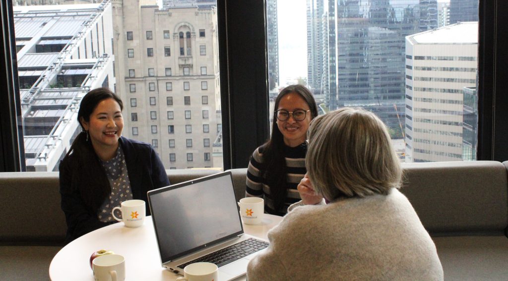 Group of employees sitting around a table with a large window behind