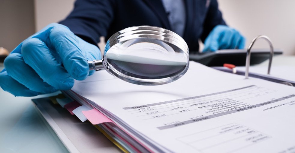 Magnifying glass inspecting business paperwork