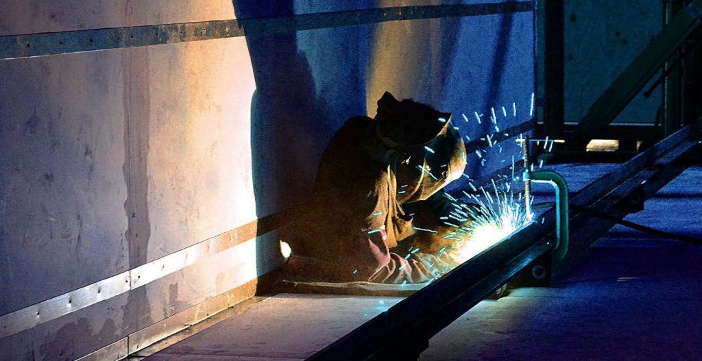 Welder working on a pipe with sparks flying around