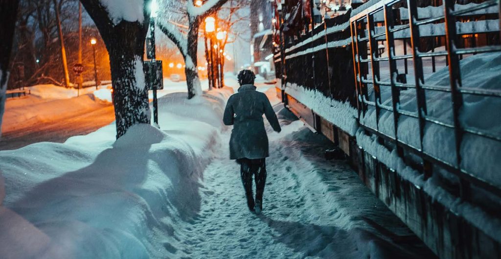 Snowy street with someone walking down the sidewalk