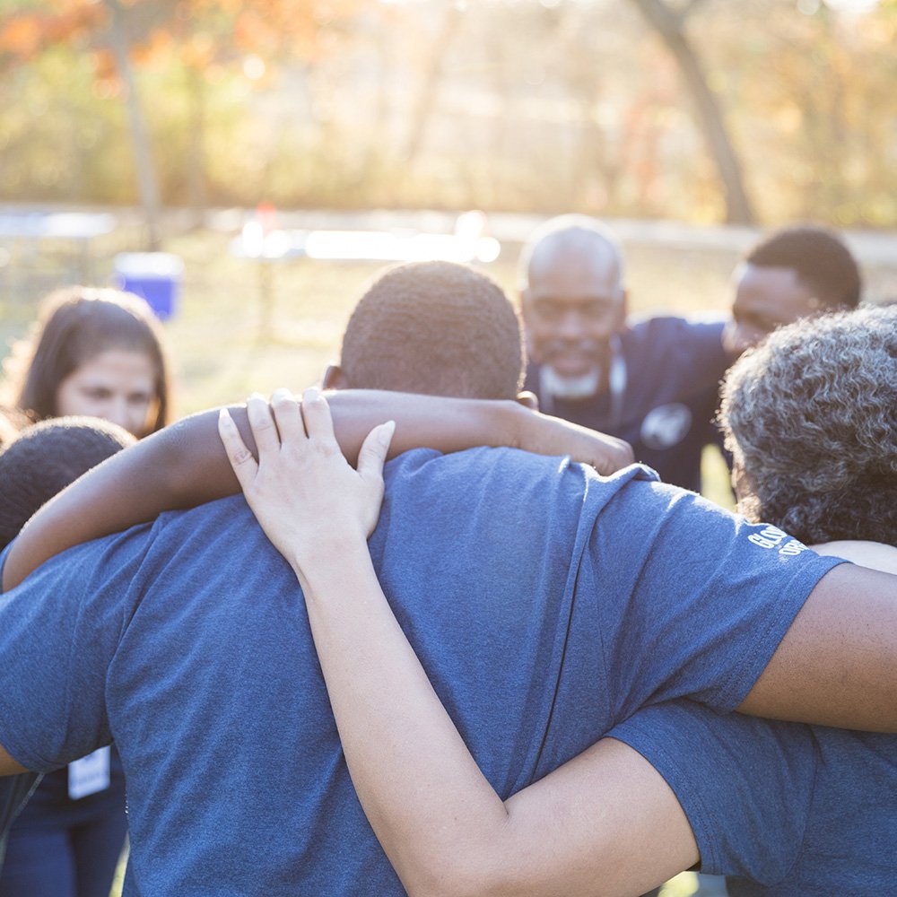 Group of volunteers in a huddle with arms around each other