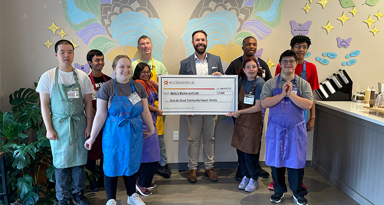 IMG_0420 Group of employees surround a person holding a giant novelty cheque in a cafe