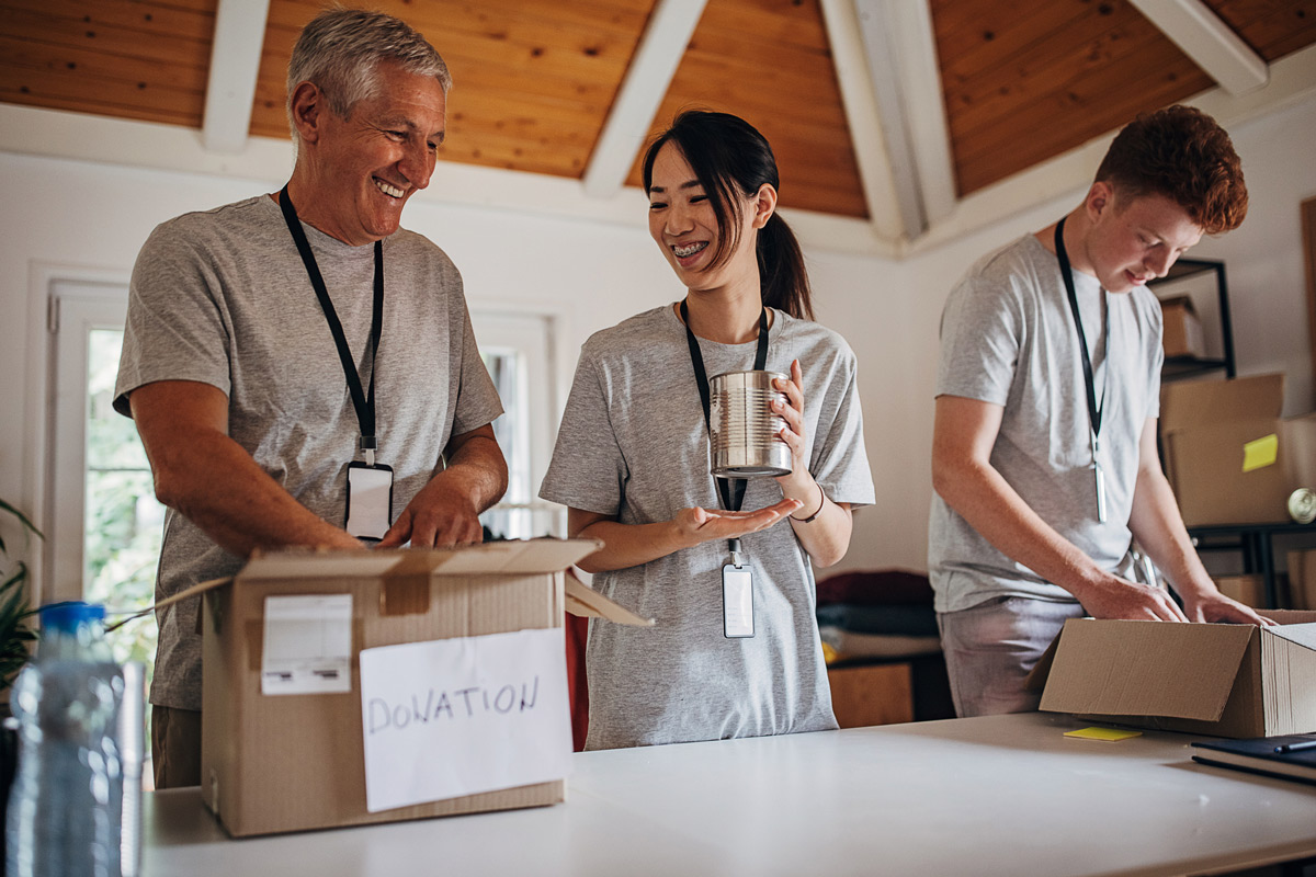 Three volunteers pack boxes of canned goods for donation