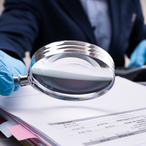 Someone uses a magnifying glass to look over important documents