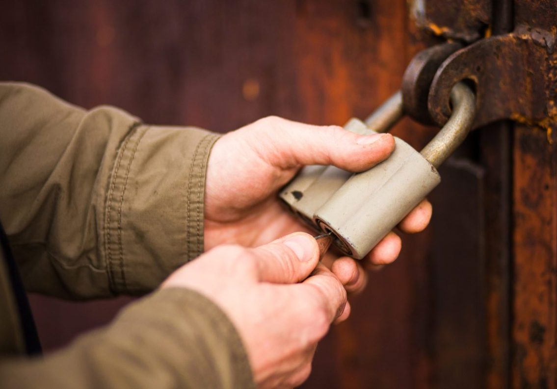 Close up angle of someone securing a lock on a wooden door