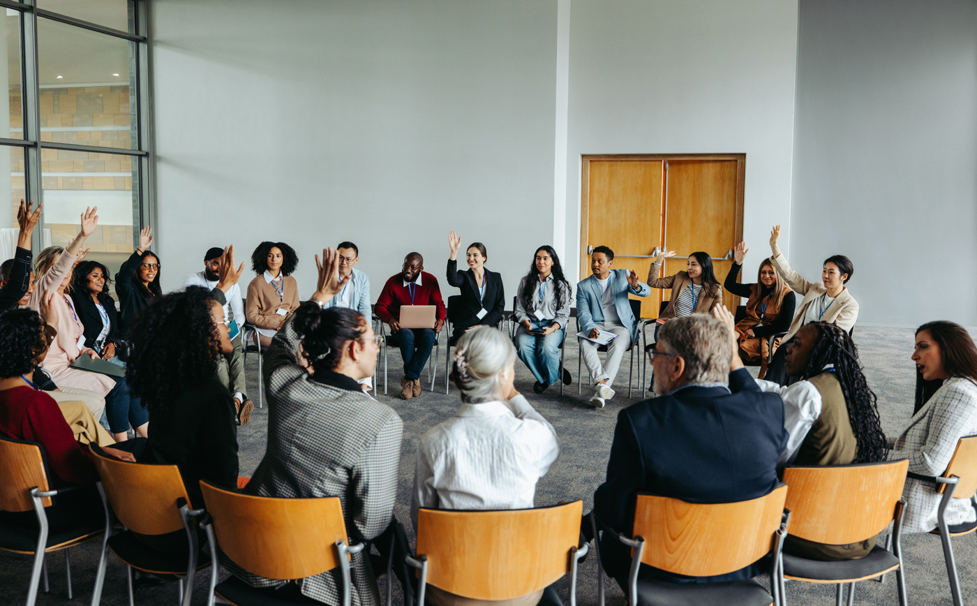 A diverse group sits in a circle having a discussion as part of a group therapy session