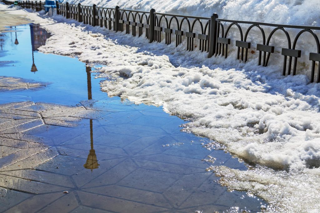 A walkway covered with melting snow and puddles of water