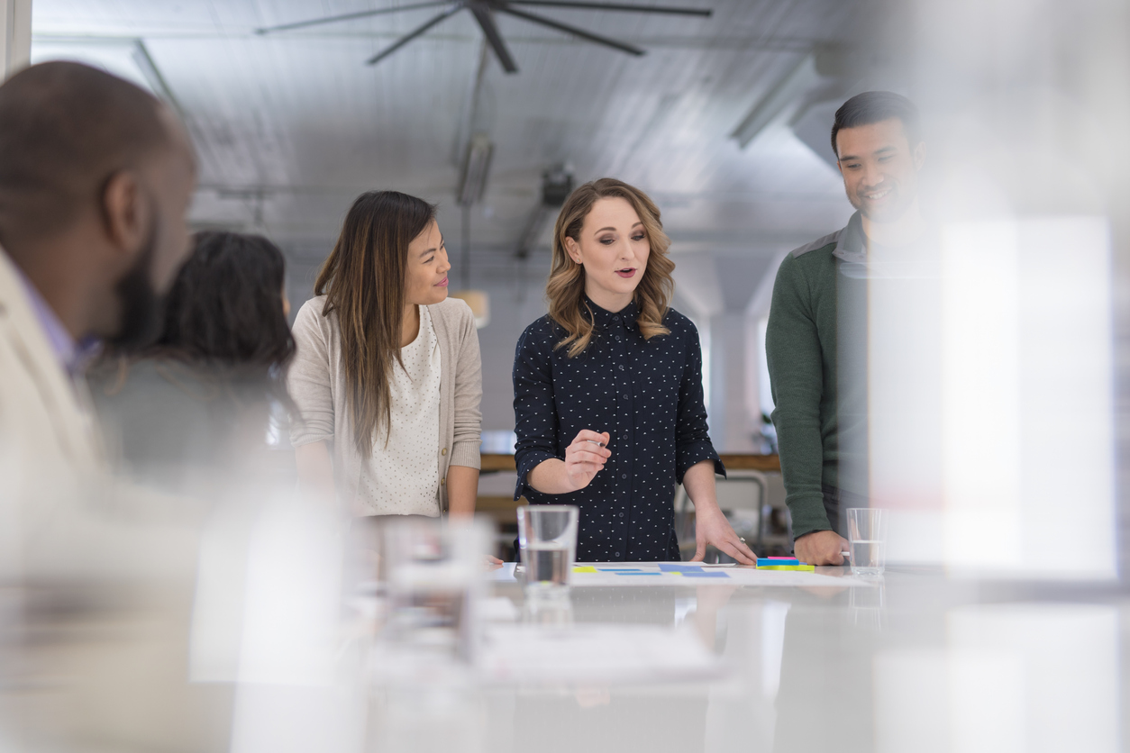 A mixed-ethnic group of business colleagues sign paperwork at the conference table Group of coworkers around a desk having a serious discussion