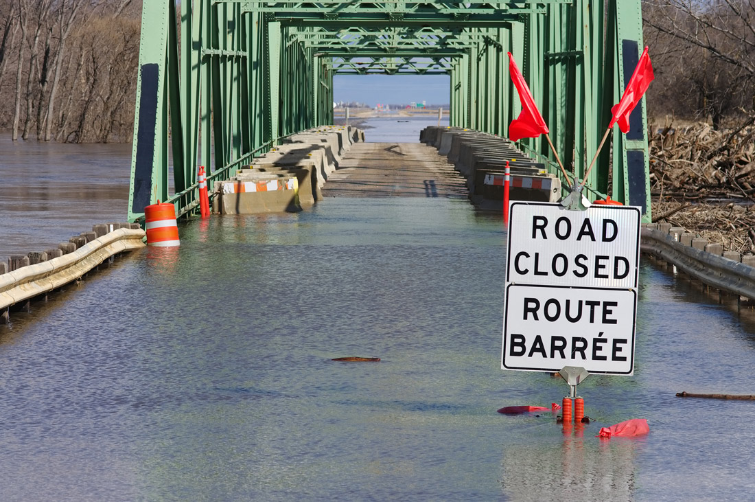 A "road closed" sign on a flooded bridge