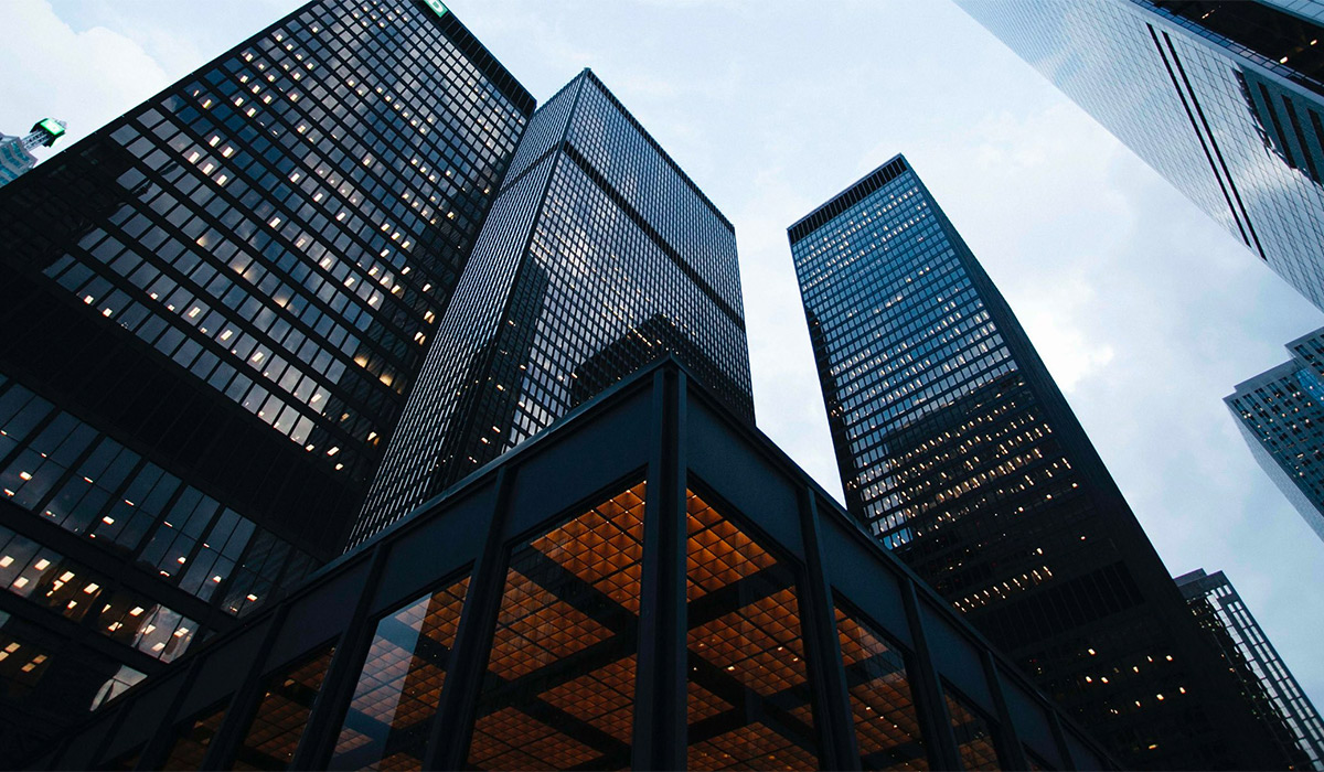 Looking up at tall, dark skyscrapers against a cloudy sky