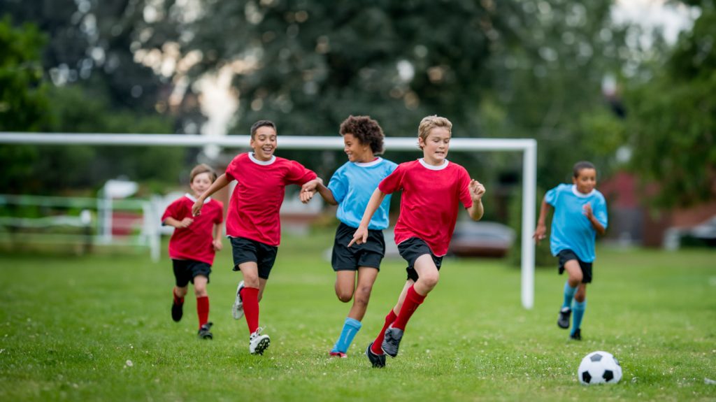 Group of young kids in blue and red jerseys playing soccer