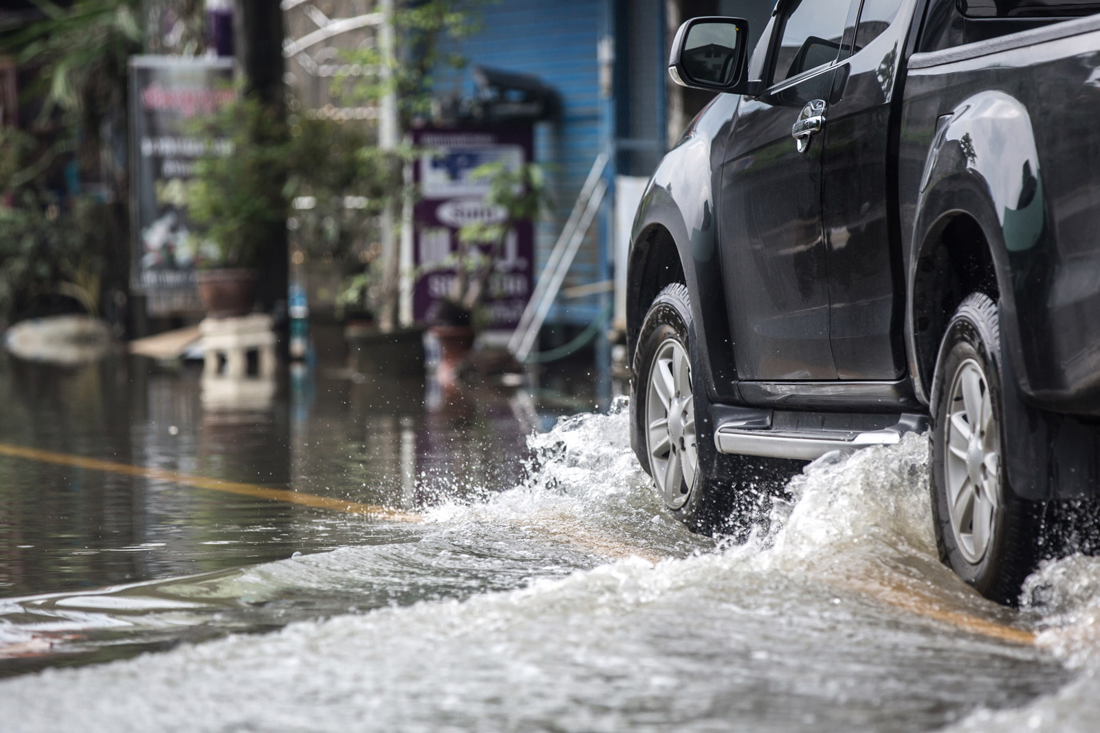 View of the side of a vehicle driving down a flooded street