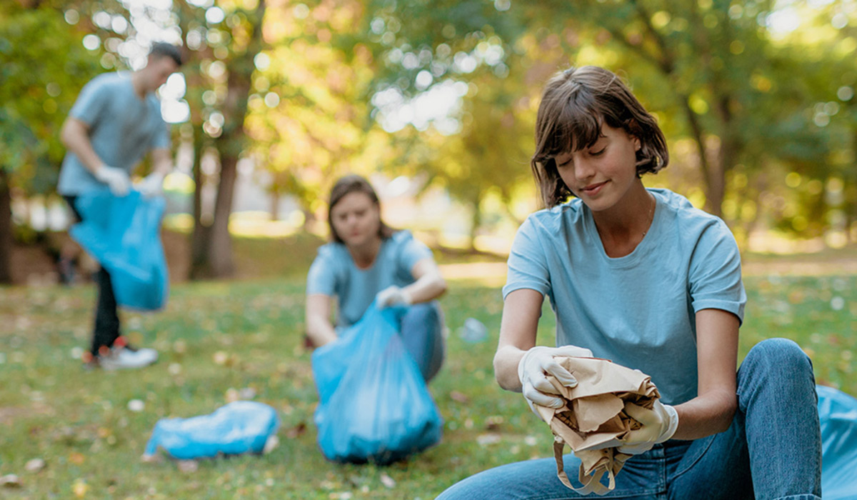 Three volunteers pick up garbage in a park