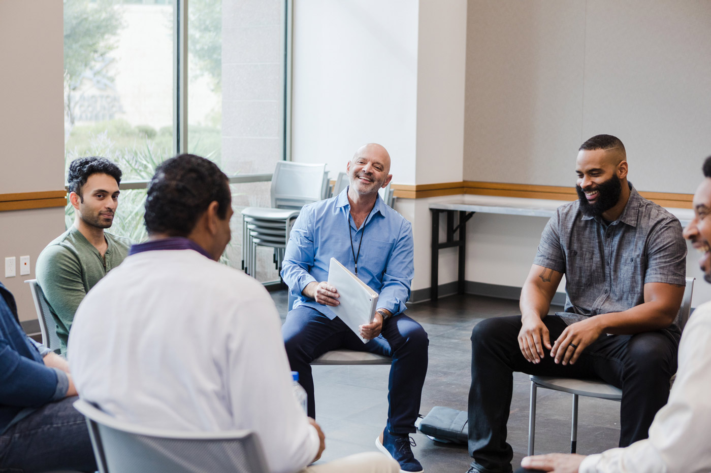 wellbeing-01 Group of men sitting in a circle at a support group meeting