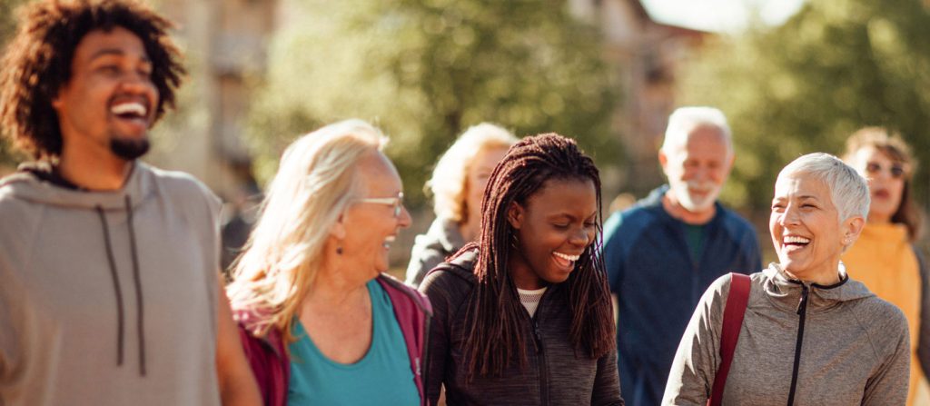 Group of four diverse friends walking outdoors and laughing