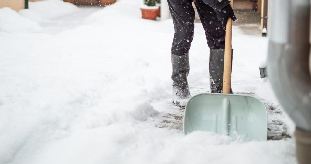 Person with a shovel on a snowy walkway